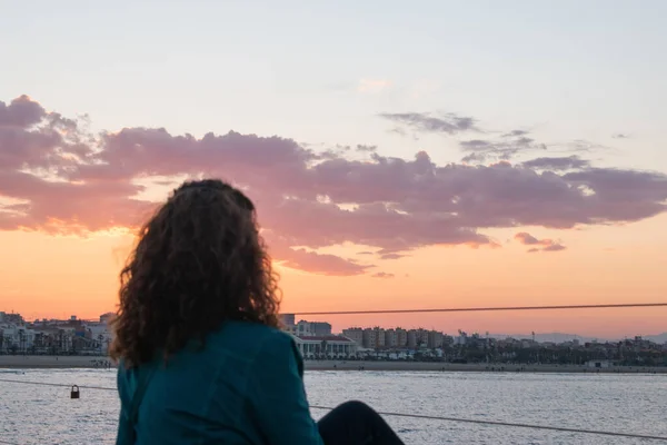 Silhouette of a seated woman looking at sunset