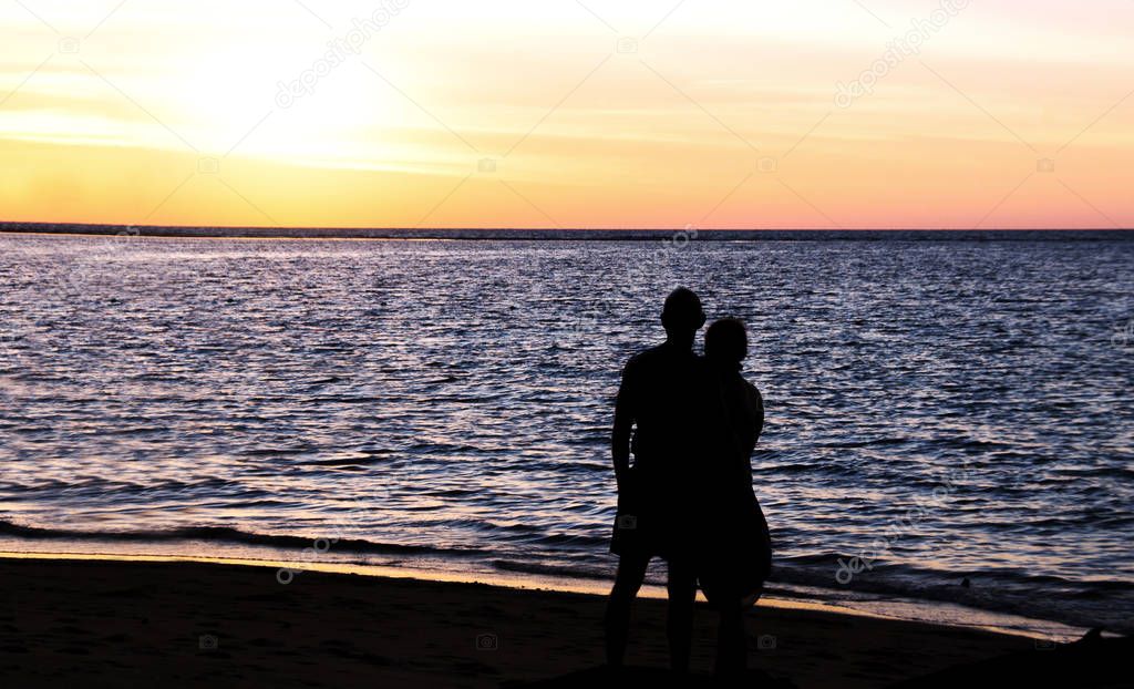 silhouette man and woman hug on the beach