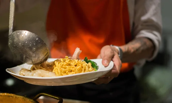 Mano de chelf poner sopa en fideos crujientes — Foto de Stock