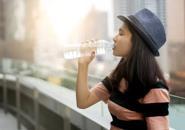 asian girl drinking water from bottle in morning light