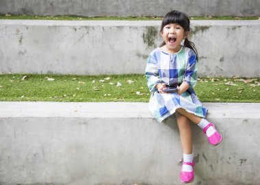 Asyalı çocuk oynamak Bahçe park akıllı telefon