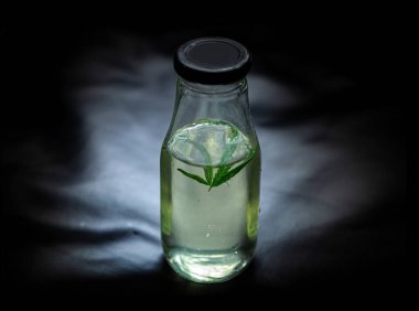 Karanlık arka plan tıbbi kavramlarına, alternatif tıp, cbd yağı, eczacılık ve terapi endüstrilerine yerleştirilen kenevir suyu ve kenevir yaprakları..