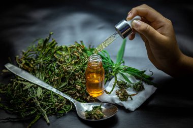 Esmer arka plana yerleştirilen kenevir yağı ve kenevir yaprakları, tıbbi kavramlar, alternatif tıp, cbd yağı, eczacılık ve terapi endüstrileri.
