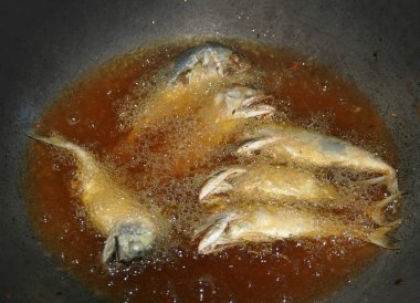 Tavada sıcak yağlı balıkla deniz ürünleri menüsü hazırlıyorum.