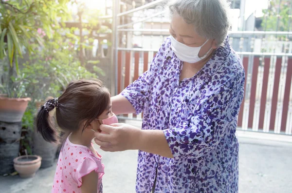 grand parent taking face mask to kids for protect corona virus pandemic before go outside home
