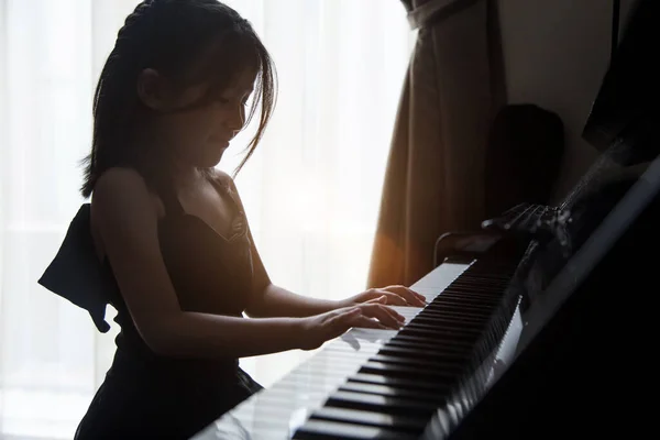 아시아 소녀들은 직업을 구하기 능력을 향상시키기 위하여 피아노 연습을 — 스톡 사진