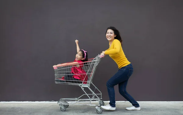 happy asian mother and daugther love shopping action with shopping cart on blank background.