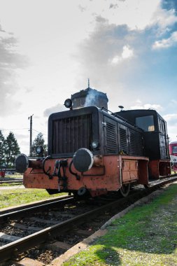 Demiryolundaki siyah ve eski dizel lokomotif. Arka planda darmatik bulutlu mavi gökyüzü