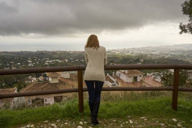 Zarif elbiseli bir kız dağlarda durup manzarayı seyrediyor.