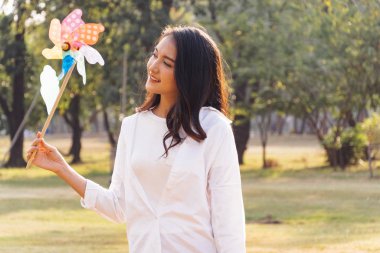 Güneşli bir günde parkta türbin çalan mutlu Asyalı kadın yüzünde güzel bir gülümseme, hafta sonu konseptine zaman harcayıp rahatlatıyor.