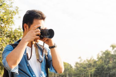 Asyalı fotoğrafçı, park, seyahat, serbest meslek hayatı ya da boş zaman aktivitesi konsepti, fotokopi alanı ile dışarıda kamerayla manzara fotoğrafı çekiyor.