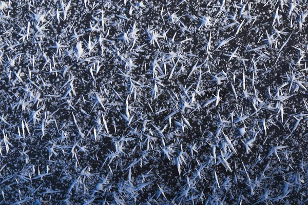 Hermosos macrocristales de hielo blanco en la superficie helada oscura — Foto de Stock