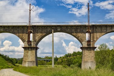 Parlak yaz gününde bulutlu bir gökyüzünün arka planda nehir Sluch karşısında pitoresk eski kemerli demiryolu köprüsü. Ukrayna