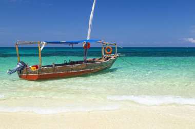 Eski bir Afrika teknesi, yakın plan. Mavi parlak arka planda, gök mavisi okyanus yüzeyinde bir tekne. Zanzibar adası kıyıları, Afrika