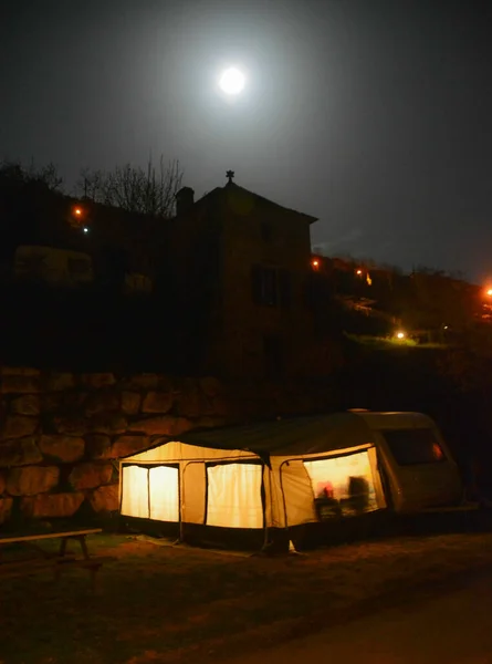 Caravan in the light of the full moon at a camp in France, Europe, with a tower on top.