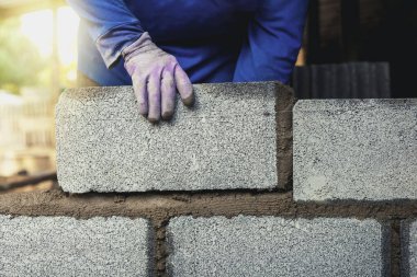 İnşaat işçileri tuğla bloklarla beton duvarlar inşa ediyorlar..