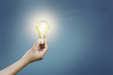 Ampul el ele çimento duvar arkaplanı Enerji tasarrufu kavramı