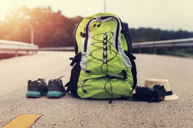 Sırt çantalı ve şapkalı bir gezgin. Güneş batımı, seyahat konsepti. Kamera aksesuarları.