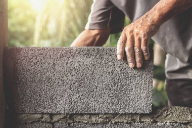 İnşaat işçileri tuğla bloklarla beton duvarlar inşa ediyorlar..