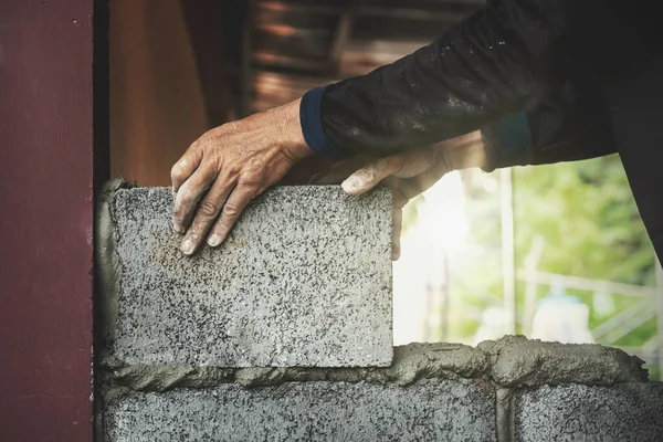 İnşaat işçileri tuğla bloklarla beton duvarlar inşa ediyorlar..