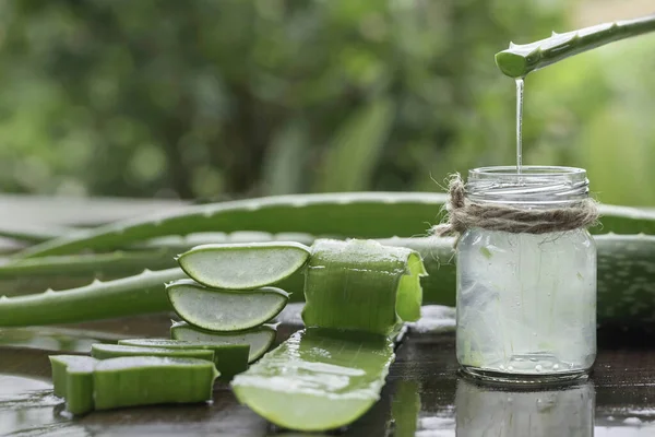 Aloe Vera yaprakları ve ahşap zemine bir bardak su.