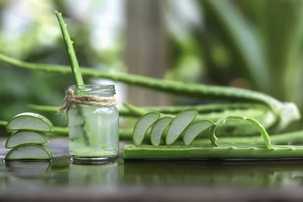Aloe Vera yaprakları ve ahşap zemine bir bardak su.