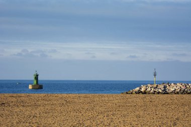 Kumsalın fotoğrafı, kumlu, bulutlu gökyüzü ve güneş ışığı.