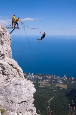 Ukrayna, Kırım, 20 Haziran 2013. İp atlama aşırı yüksekten atlıyor. Bir adamın uçurumdan atlayıp denizin arka planındaki uçuruma atlamasını sağlayın.