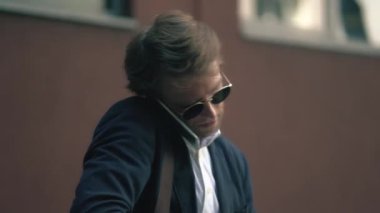 Tarz sahibi adam cep telefonuyla konuşurken defterine bir şeyler yazıyor.