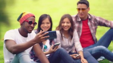 Arkadaş öğrenciler üniversite arka planında otururken akıllı telefondan komik videolar izliyorlar.