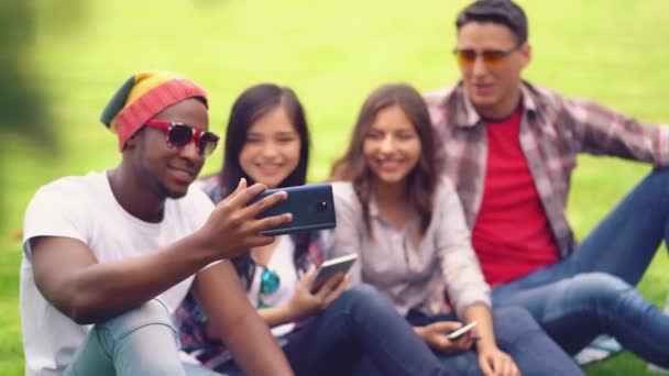 Vänner studenter tittar på roliga videor på en väns smartphone medan du sitter på en universitetsbakgrund — Stockvideo