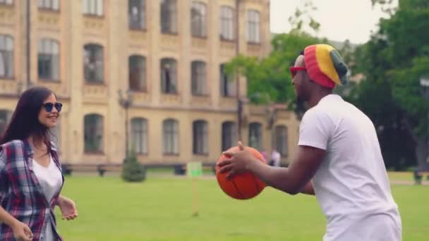 Mladí lidé hrají házet jeden druhého míč venku v parku Univercity — Stock video
