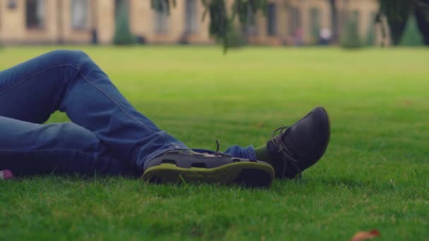 Joven descansando en el suelo en una hierba verde . — Vídeo de stock
