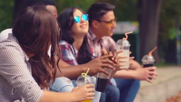 Estudantes felizes de colagem masculina e feminina bebem suco fresco e sorriem — Vídeo de Stock