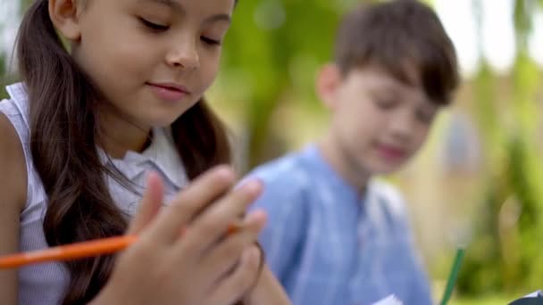 Kids sitting outdoor and doing homework — Stock Video