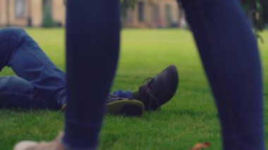 Yaklaş erkek bacaklarına kot pantolon içinde yeşil çimlere uzanmış