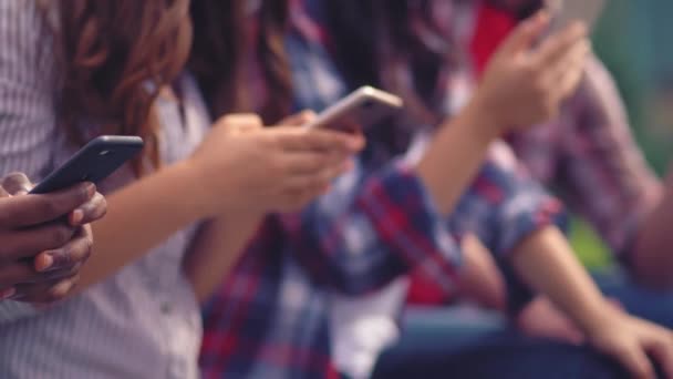 Grupp ungdomar med smartphones i hads utomhus — Stockvideo