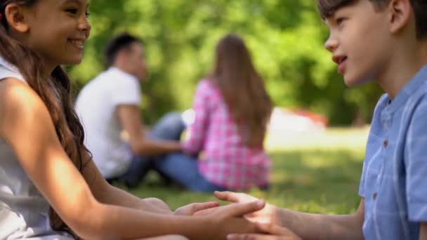 子供男の子と女の子遊びますPat Cake座っています上の草の上にザ姉とともに彼女のボーイフレンド — ストック動画