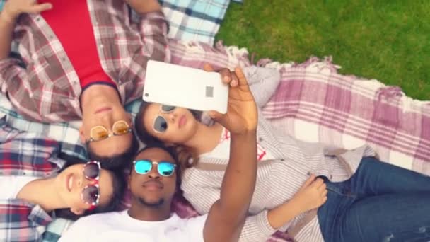 Overhead view of group taking selfie lying on plaid outdoors — Stock Video
