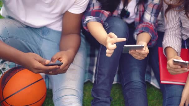 Vrienden sms 'en met mobieltjes op campus park — Stockvideo