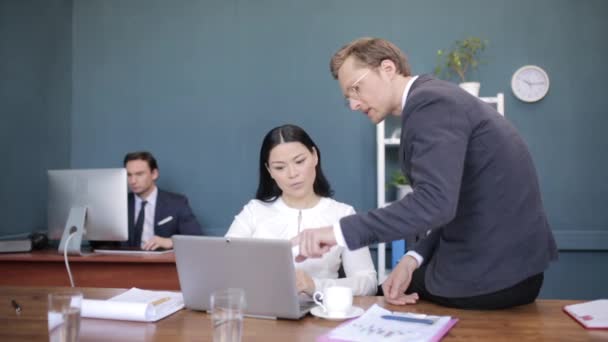 Προσεκτικοί Διαφορετικοί Επιχειρηματίες συζητούν πάνω από ένα φορητό υπολογιστή στο γραφείο — Αρχείο Βίντεο