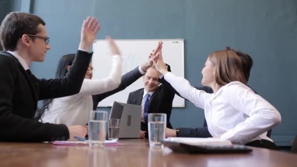 Pessoas de negócios sorrindo fazendo high-five enquanto se senta com colegas — Vídeo de Stock