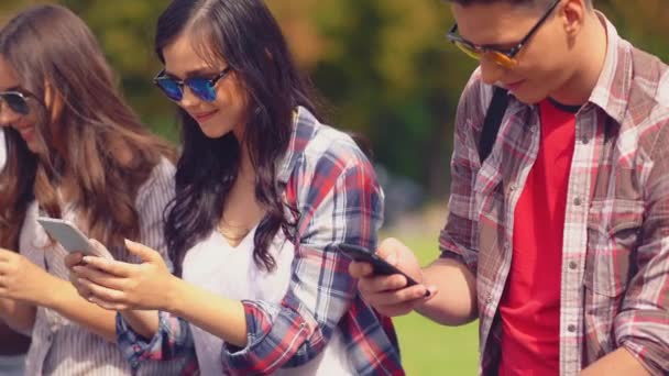 Przyjaciele z college 'u korzystający ze smartfonów SMS-ów spędzających czas w mieście — Wideo stockowe