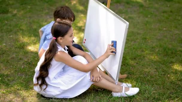 Allievi che disegnano su una tavola bianca all'aperto — Video Stock