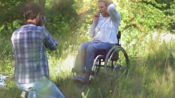 Ehemann fotografiert eine schöne Peitsche im Rollstuhl. — Stockvideo