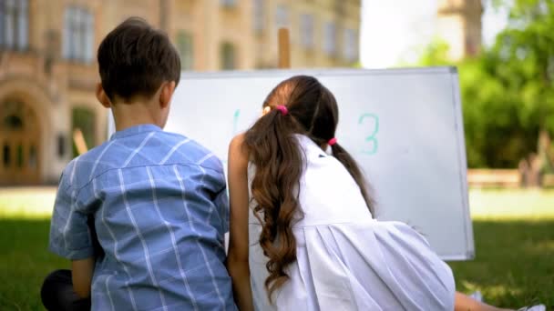 Kinderen die getallen bestuderen zitten buiten. — Stockvideo