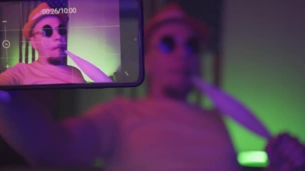 Man med smartphone gör vinstockar videor i neon ljus rum — Stockvideo