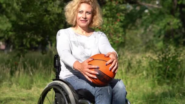 Woman in a wheel chair holding a ball for kids — Stock Video