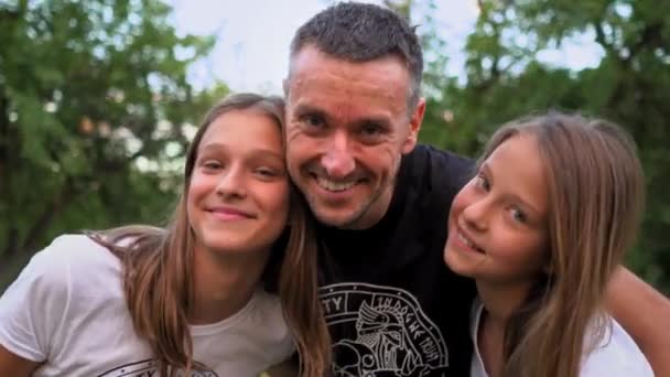 Отец обнимает своих дочерей-подростков — стоковое видео