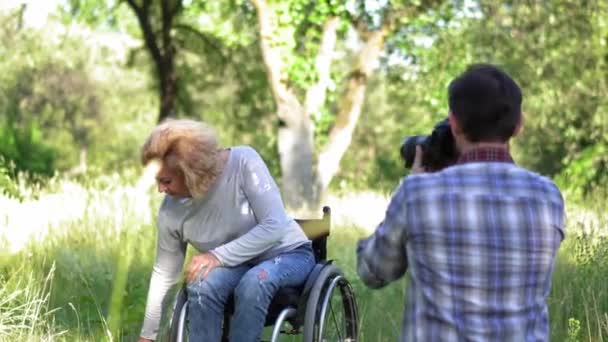 Esposo haciendo fotos de su esposa en una silla de ruedas . — Vídeos de Stock